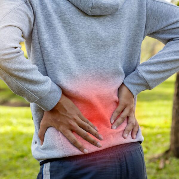 man in sweatshirt holding his back in pain