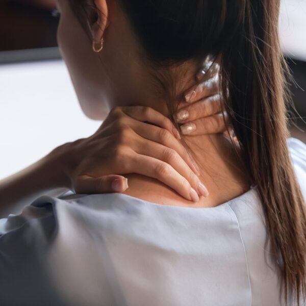 Woman touching her neck in pain while working at a computer